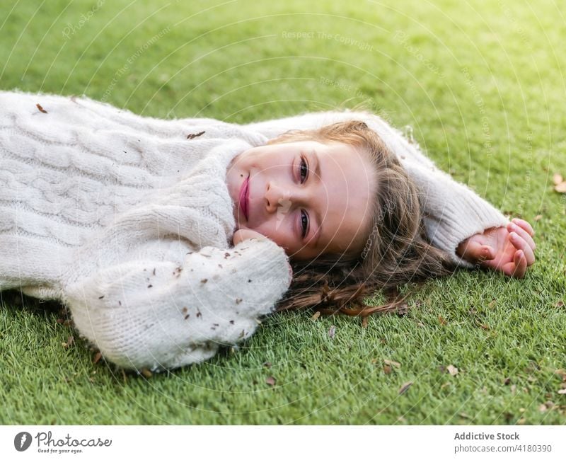 Carefree girl lying on grass in backyard smile grassland cute cheerful carefree meadow nature positive optimist beautiful leisure childhood grassy sweater white