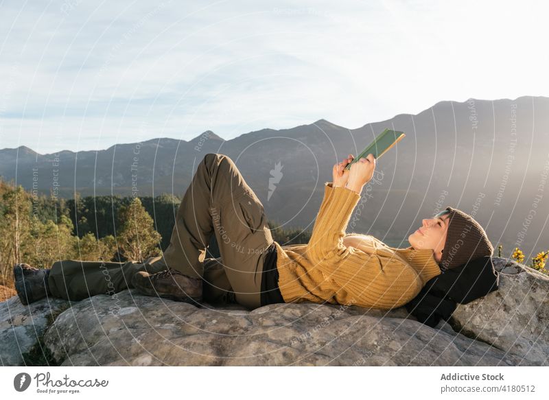 Traveling woman reading book in mountains travel drink beverage highland enjoy harmony female traveler lying cup hot interesting spectacular vacation comfort
