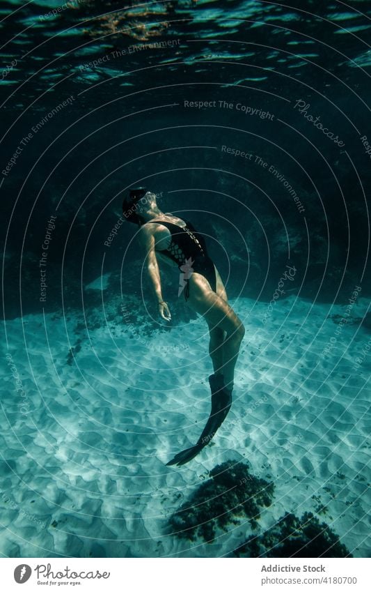 Woman swimming underwater in sea woman flipper dive swimsuit grace slim undersea female swimmer swimwear summer diver turquoise color deep bottom sand lady