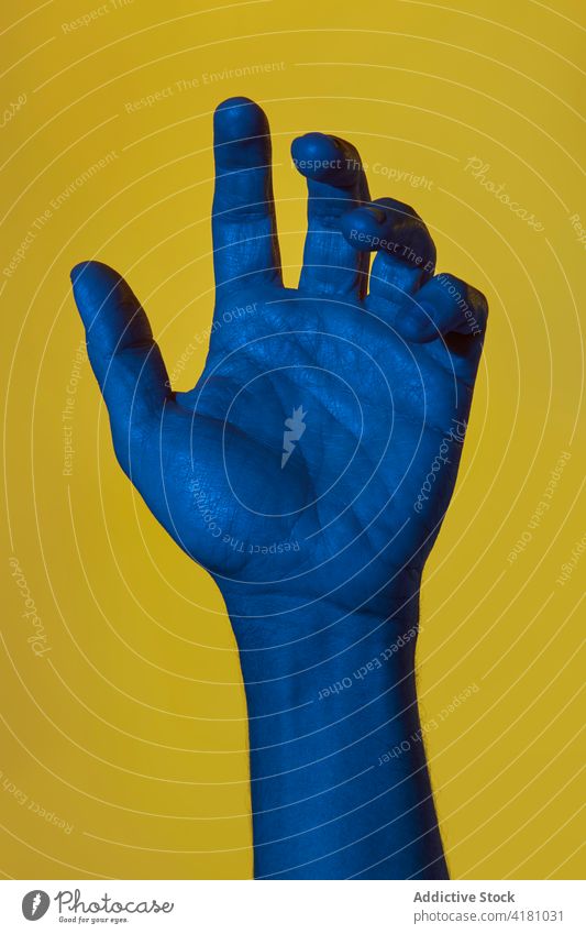 Man's blue hand with open palm man dark blue over yellow background pop art showing concepts isolated copyspace male person fingers human hand adult wrist
