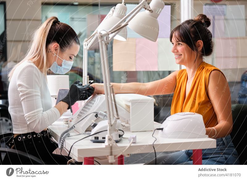 Happy woman getting manicure procedure in beauty salon client master professional service happy treat cheerful work tool specialist female lifestyle equipment