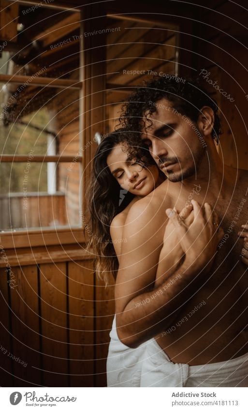 Gentle woman embracing shirtless boyfriend during honeymoon in hut couple embrace relationship love spend time fondness tender enjoy towel naked torso
