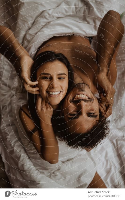 Happy undressed couple sitting back to back on blanket cheerful romantic toothy smile love naked cuddle affection intimate relationship together lying soft