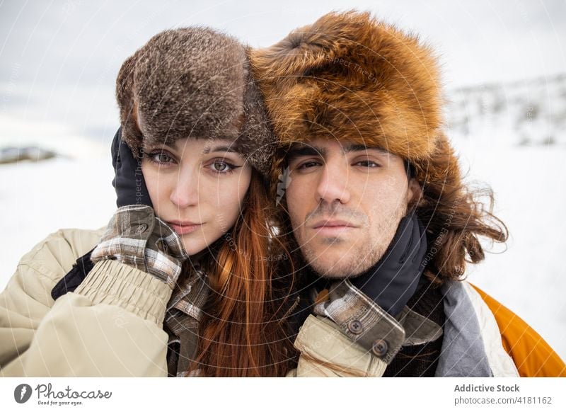 Couple in fur hats embracing against snowy mountain couple embrace love relationship spend time weekend tourism winter portrait harmony boyfriend girlfriend