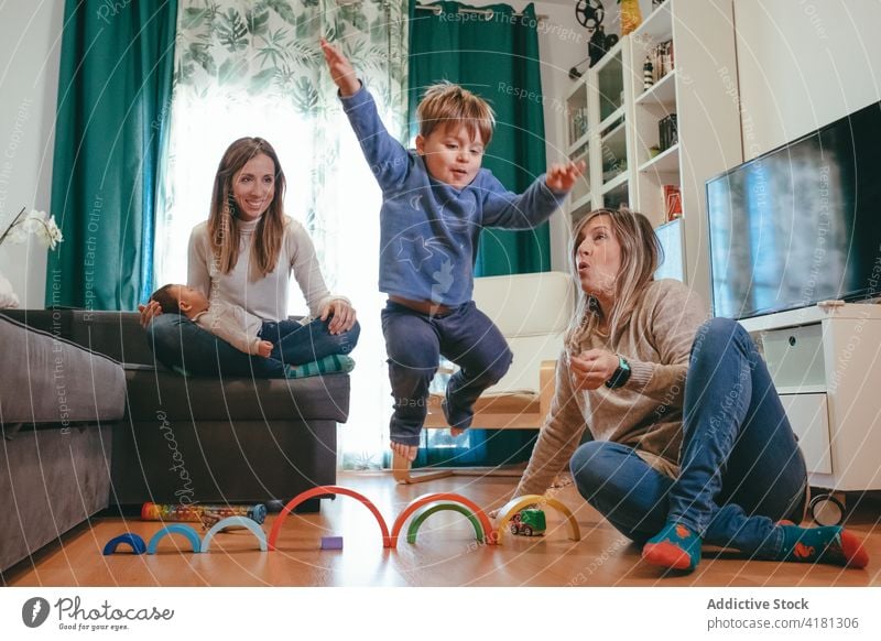 Cheerful homosexual family playing with cute kids at home couple lesbian happy having fun free time living room carefree parent parenthood generation mother