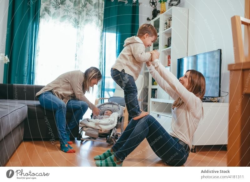 Happy homosexual family playing with kids in living room couple lesbian son smile happy carefree having fun parent mother childcare alternative lgbtq joy