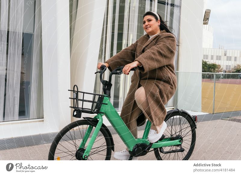 Plump woman with bicycle walking on urban pavement contemplate spare time weekend stroll autumn city casual style bike basket vehicle transport coat footwear