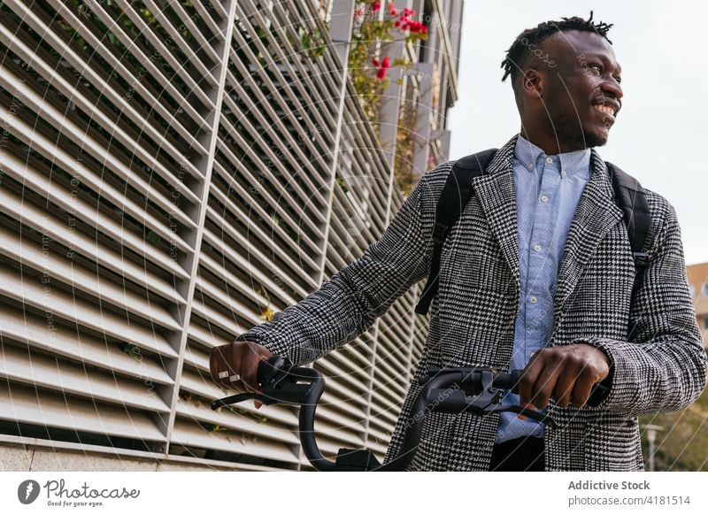 Cheerful black office worker with bicycle on city street man cheerful formal style vehicle pavement friendly town african american wall ribbed ethnic smile