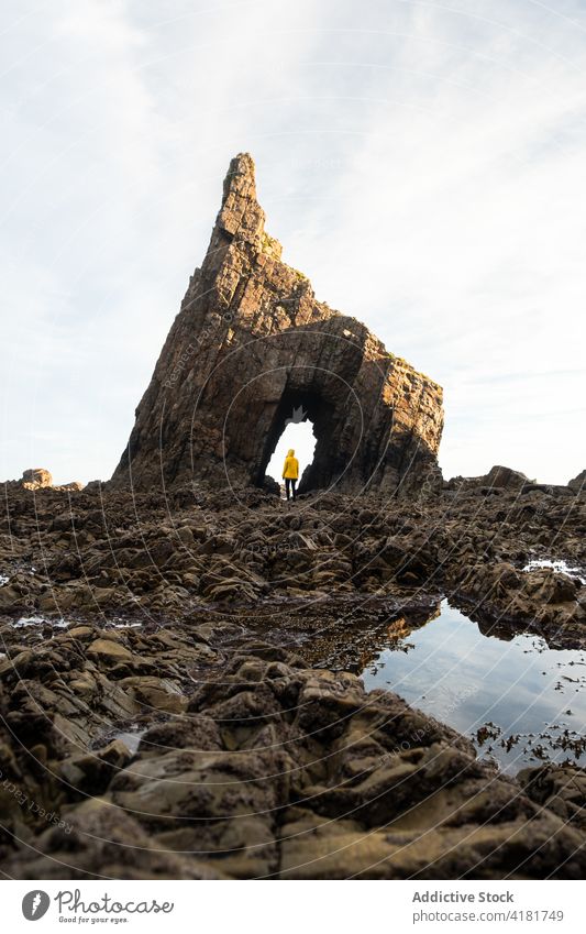Person standing in arch of natural rocky formation on shore traveler hole explore mountain rough highland autumn geology wanderlust nature asturias spain