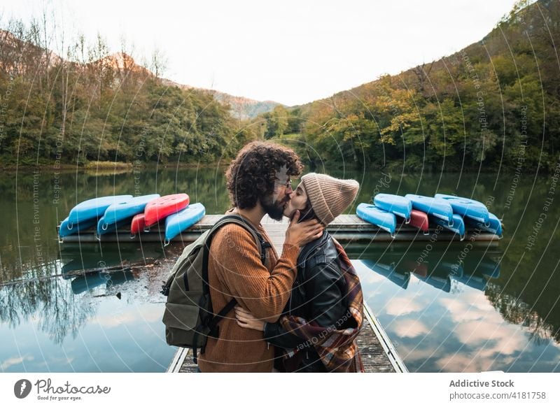 Romantic couple kissing on lake pier surrounded by verdant forest reservoir valdemurio relationship love tender lakeside nature romantic quay together young