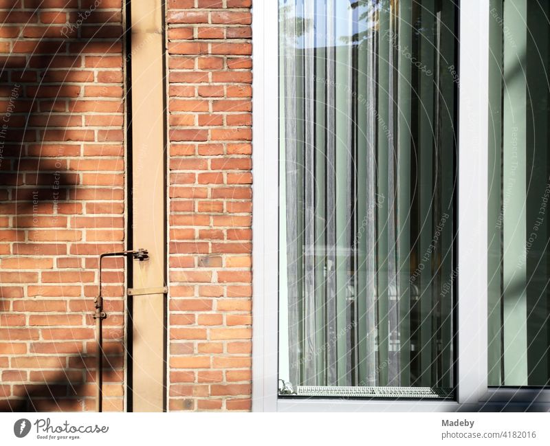 Brick facade with large window and lamellas as sun protection in sunshine in Bielefeld in the Teutoburg Forest in East Westphalia-Lippe Facade clinker