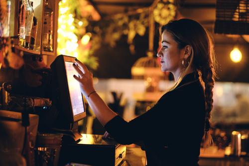 a beautiful young woman at the desk in a restaurant standing touching female cash register pay manage bar lifestyle touchscreen using bill business management