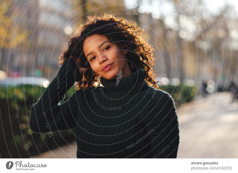Young woman standing outdoors on the street. young urban sombrero style city closeup curly hair hairstyle warm clothing trendy one posing confident casual