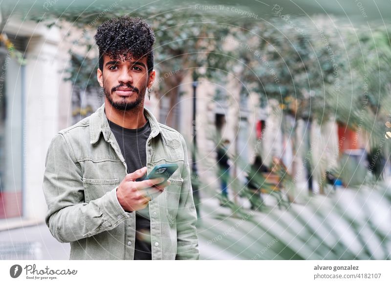 a young hipsanic man using his mobile phone outdoors in a cloudy day communication che happy technology male latin hispanic adult people smartphone lifestyle