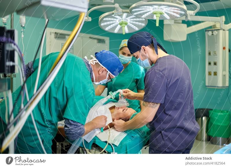 Unrecognizable male doctor giving anesthesia to patient lying on couch before surgery man doctors operating room teamwork control clinic treat medical uniform
