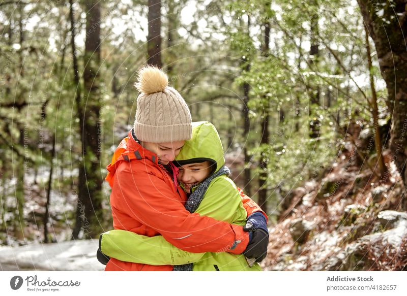Cheerful siblings hugging in snowy forest together smile happy warm clothes winter rela friend peaceful frozen woods nature love embrace cheerful cold joy frost