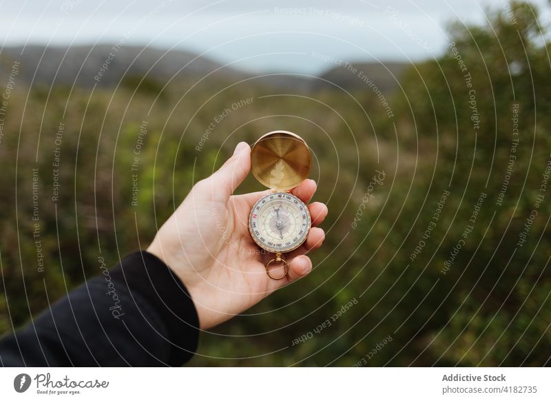Faceless traveler opening compass on mount during trip tourist orientate direction navigation guide indicate woman vacation show golden creative design arrow