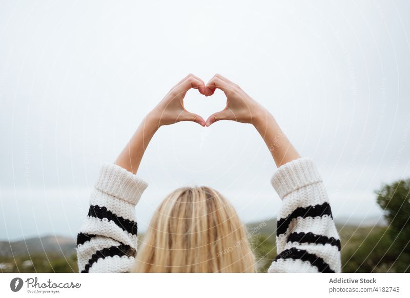 Crop traveler showing heart gesture against mountain love arms raised nature sky trip woman ornament knitwear valentine perfect idyllic harmony romantic amour