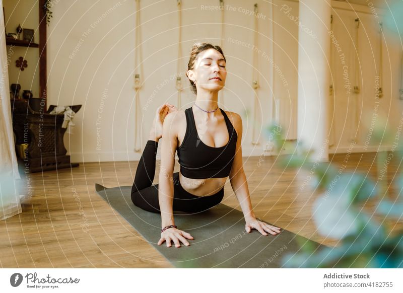 Mindful woman showing King Cobra pose at home king cobra yoga stretch concentrate practice healthy lifestyle eyes closed backbend house flexible energy wellness