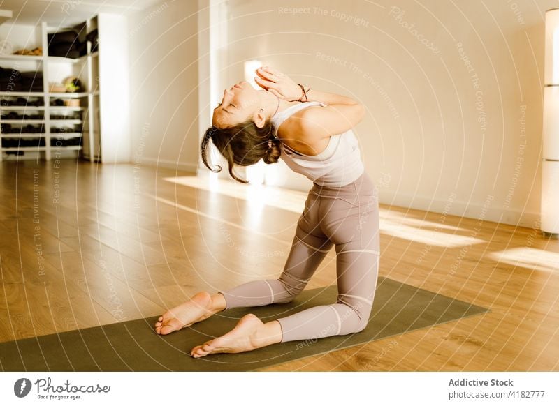 Flexible woman performing backbend with raised arms on yoga mat arms raised practice flexible stretch wellness healthy lifestyle house camel pose asana fit body