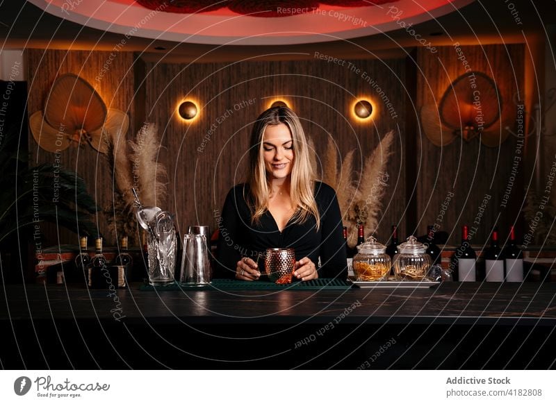 Stylish young woman preparing alcoholic cocktail in modern bar prepare self assured style confident drink barkeeper gorgeous metal mug charismatic female blond