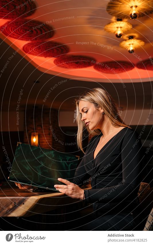 Confident young lady reading menu in modern restaurant woman bar confident concentrate style relax choose client serious interior nightlife female elegant