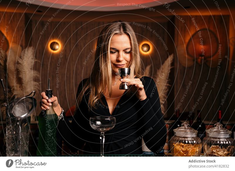 Confident young lady smelling alcohol drink during cocktail preparation in bar woman jigger bartender prepare allure positive confident content work female