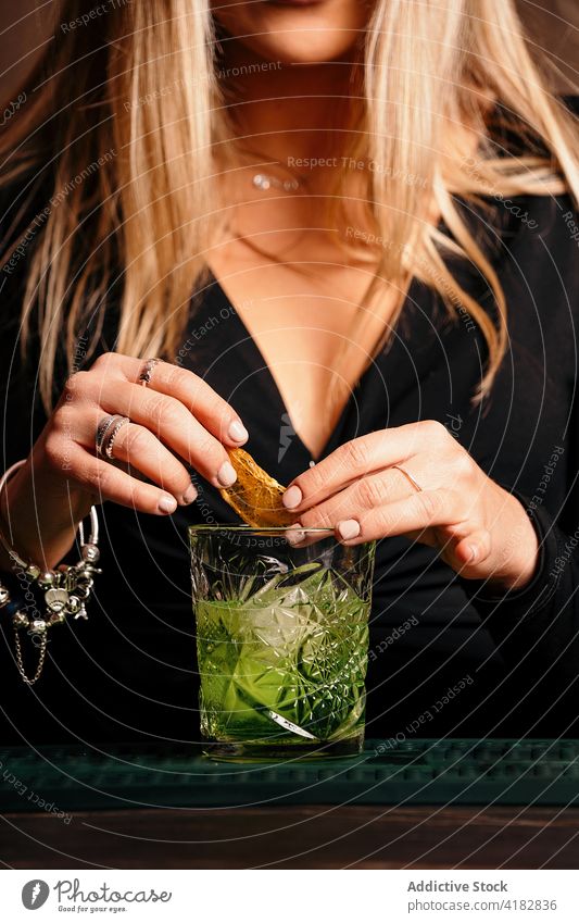Stylish young woman preparing alcoholic cocktail in modern bar prepare style drink barkeeper female beverage trendy focus decorate lemon slice interior counter