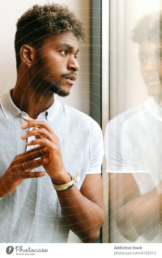 Pensive ethnic man looking at window pensive thoughtful serious beard curly hair contemplate think young black african american male dream lifestyle ponder