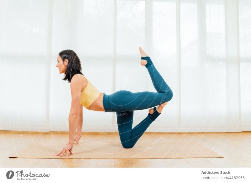 Woman doing balancing posture during training sportswoman stretch balance position wellbeing healthy physical activity wellness energy concentrate practice yoga