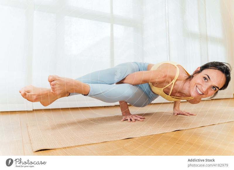 Positive sportswoman practicing Eight Angle position yoga asana eight angle optimist advanced balance healthy lifestyle wellness female sportswear astavakrasana