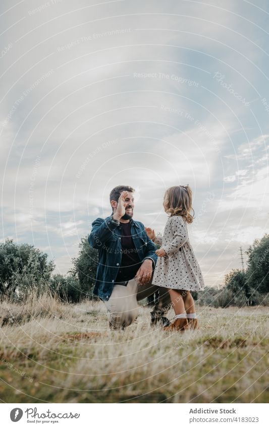 Happy father and daughter having fun in field high five gesture together weekend nature countryside little girl cute love cheerful relationship parent kid child
