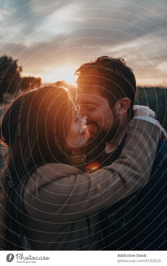 Couple kissing in field with kid at sunset couple family love relationship tender child nature weekend eyes closed happy bonding affection sky together enjoy