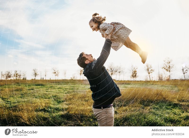 Father playing with daughter in field father child toss having fun together weekend countryside sunny cheerful cute little girl parent fatherhood relationship