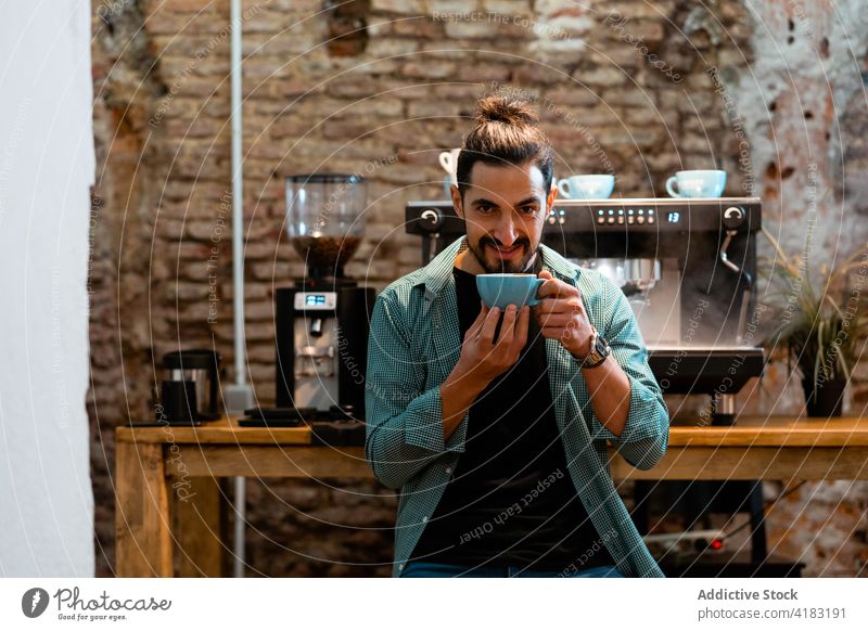Cheerful barista with cup of coffee in cafe man smell aroma smile bartender hipster drink male beverage aromatic hot happy coffee shop coffee house cafeteria