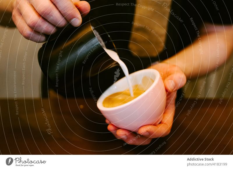 Close-up of a waiter serving milk to a cup of coffee service drink cafe cafeteria professional jug restaurant person espresso hot beverage man bar indoors male
