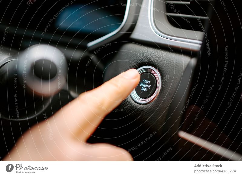 Unrecognizable man pressing button to start engine of car stop drive vehicle automobile contemporary control male hand finger dashboard steering wheel push