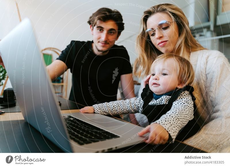Family watching movie on laptop together at home family toddler weekend couple little child table bonding sit young device joy gadget happy affection cheerful