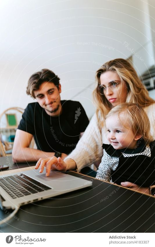 Family watching movie on laptop together at home family toddler weekend couple little child table bonding sit young device joy gadget happy affection cheerful