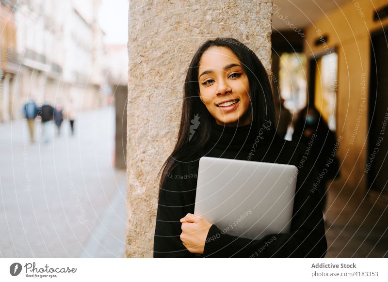 Smiling ethnic student with laptop on street woman smile city cheerful portrait content contemporary computer style female trendy gadget glad town modern