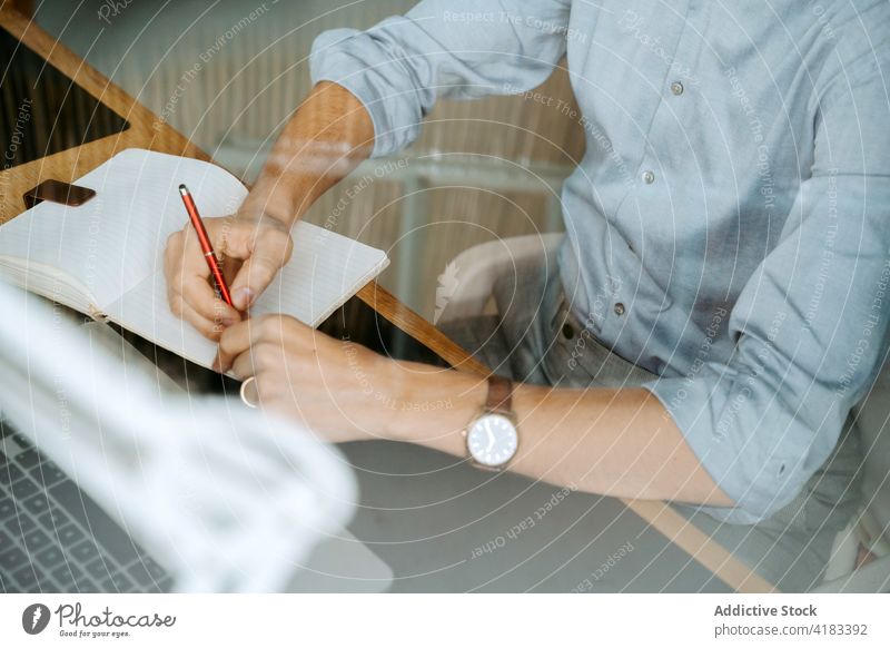 Crop businessman taking notes in notepad take note notebook plan organizer write memo entrepreneur project male table pen professional planner work career
