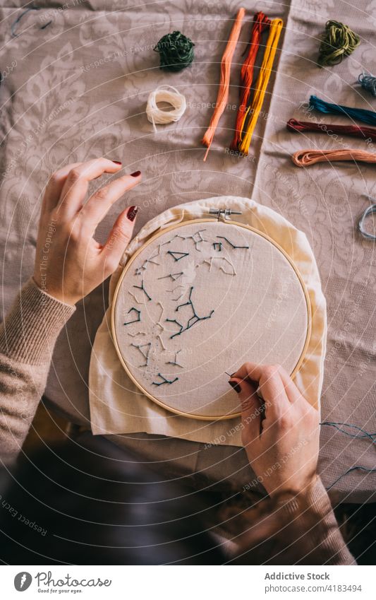 Crop faceless woman doing embroidery with hoop at home handmade thread skill hobby handwork stitch diy process needlework workshop craft table sit creative