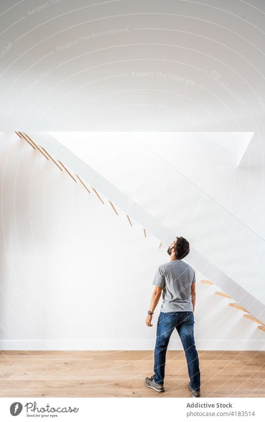 Unrecognizable man near staircase in contemporary house floor style architecture casual minimal geometry cloth jeans parquet wall building symmetry modern