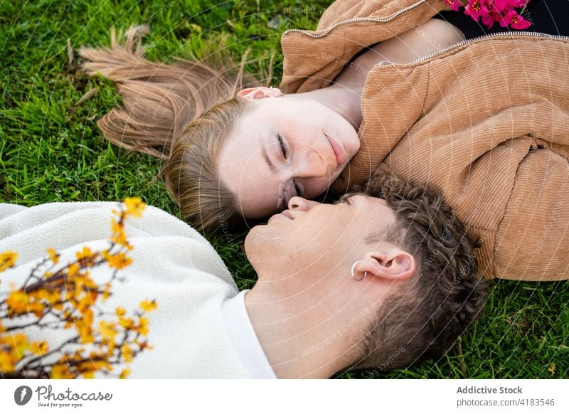 Couple with blossoming flowers lying close on meadow couple relax lawn relationship love gentle spend time summer idyllic rest spare time bright bouquet flora