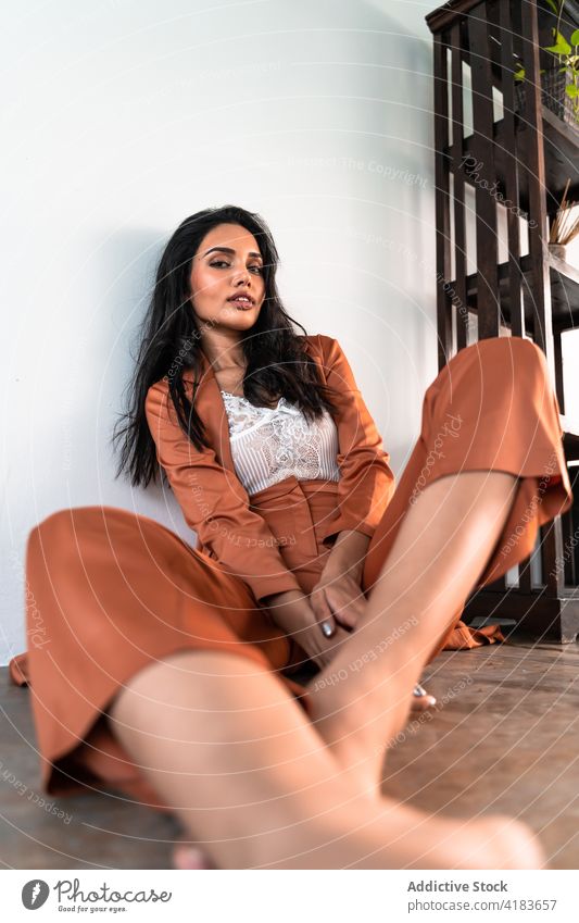 Relaxed stylish woman sitting on floor relax sensual style rest enjoy dreamy peaceful tranquil serene young ethnic female feminine calm barefoot beautiful