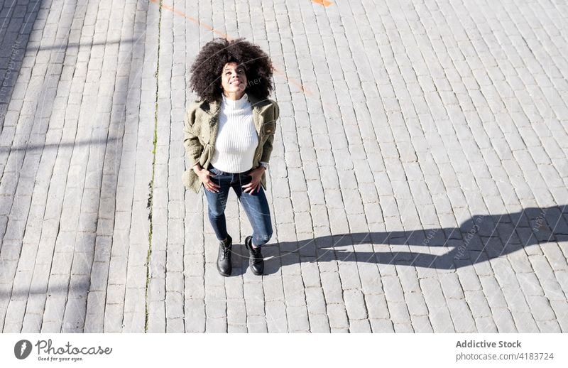Content young African American woman standing on street expressive satisfied pavement style happy smile content enjoy city female black ethnic african american
