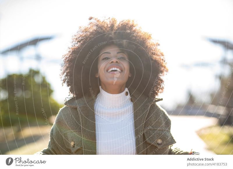Happy ethnic lady smiling while relaxing in park near lake woman smile rest lakeside cheerful style nature free time tree optimist female young african american