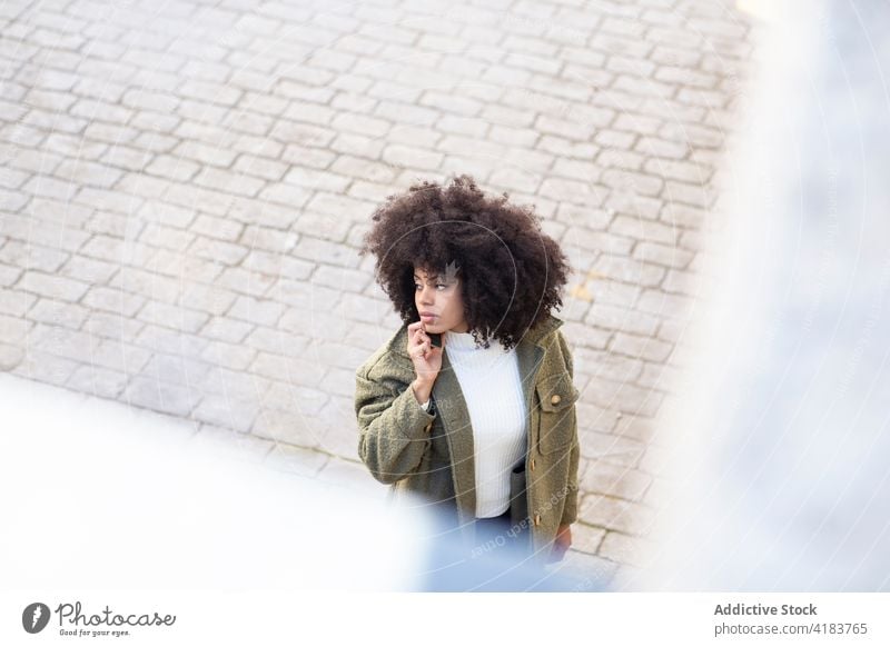 Serious young black woman walking on street and talking on smartphone phone call concentrate style conversation communicate discuss pedestrian female