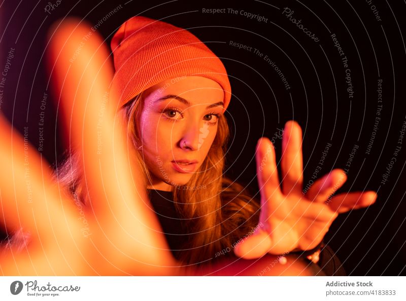 Trendy lady gesturing in studio with neon illumination woman reach out trendy concentrate gesture move style appearance cool individuality fashion female young