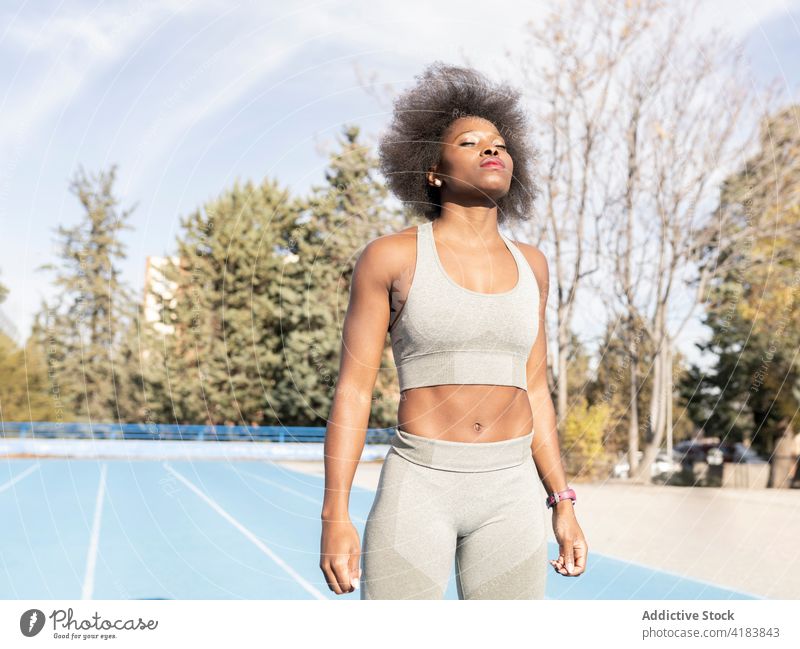 Black female athlete standing at stadium during training sportswoman confident fit runner sportswear sunny determine black african american ethnic workout